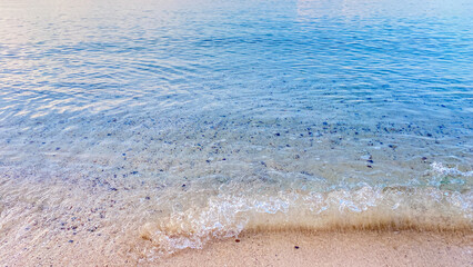 A beautiful sandy beach with soft blue ocean waves gently washing the shore.