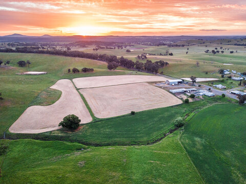 Aerial view of ploughed paddocks near farm buildings at sunset