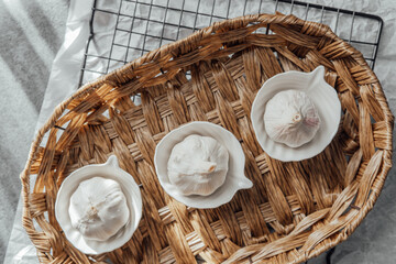 Fresh garlic bulbs displayed in white dishes on a woven tray