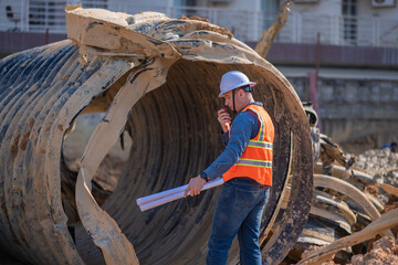 Construction surveyor or engineer working inspection damaged black corrugated pipe and construction...