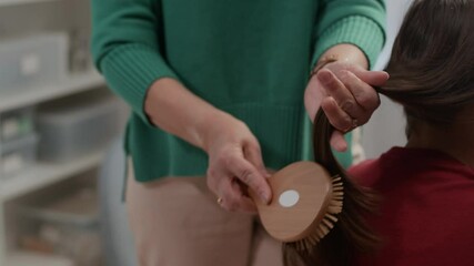 Cropped shot of unrecognizable mother brushing her daughters long dark hair indoors