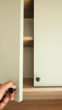 hand open a modern kitchen cabinet doors with decorative knobs