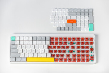 Mechanical keyboard in partial assembly with removed keycaps and exposed red switches on desk