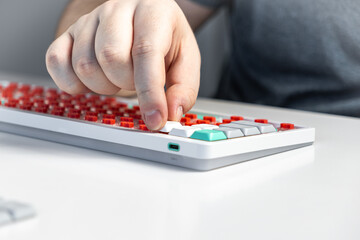Person assembling mechanical keyboard by pressing white keycap onto red switch component