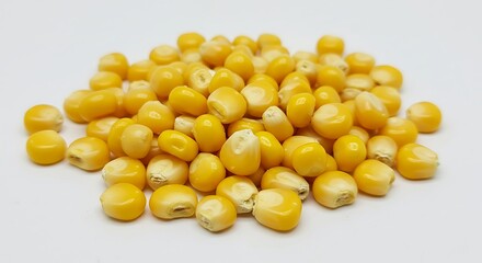 Fototapeta premium A close up shot showing a pile of yellow corn kernels on a plain white background in a studio shot