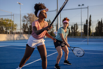 Female tennis players preparing to receive serve on blue court