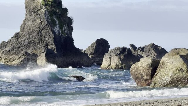 Powerful waves crash against towering rocky formations at Monro Beach, a famous spot to see rare Fiordland crested penguins (tawaki), West Coast,  Haast, New Zealand.