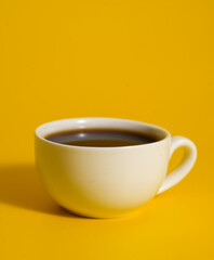 White cup of tea on yellow background