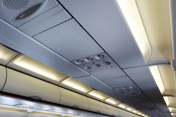 Interior atmosphere of aircraft passenger cabin perspective ceiling show overhead panel, air condition vent and fasten seat belt sign. Image use for airline business presentation background.
