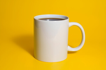 White ceramic coffee mug on yellow background