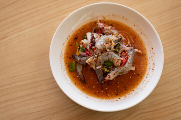 Fresh shrimp salad in a white plate placed on a wooden table.