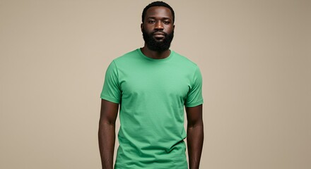 Portrait of a serious Black man in a green t-shirt against a beige background