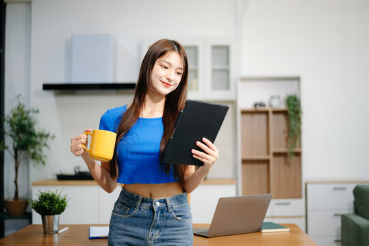 Young woman using her laptop at home in a bright kitchen. Ideal for themes of remote work