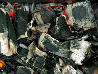 Glowing charcoal embers with cracked texture and red heat