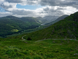 Discover the charm of Ireland's natural beauty in this photo. Gentle slopes and a twisting path create a picturesque landscape.