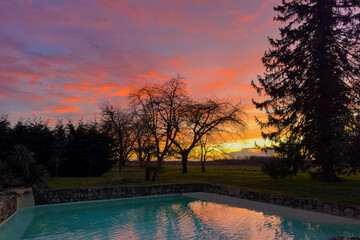 beautiful red cloudy sky sunset on countryside, swimming pool in foreground