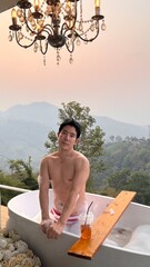 Handsome Man Relaxing in Bubble Bath with Stunning Mountain Sunset View	