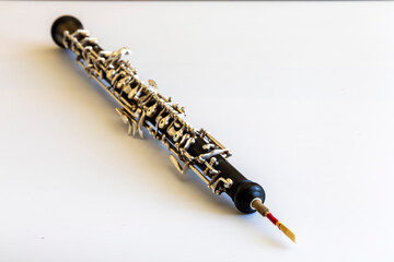 Oboe on white background, reed in foreground, body and keys are blurred