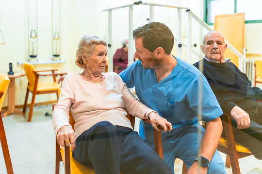Male nurse assisting elderly woman in nursing home
