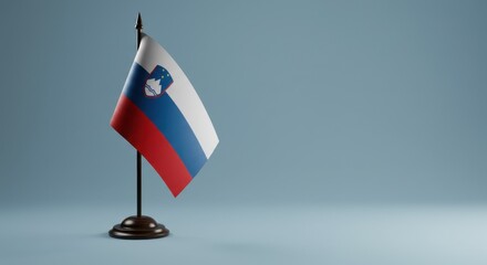 Slovenian Flag Displayed on a Desk Stand Against a Subtle Blue Background