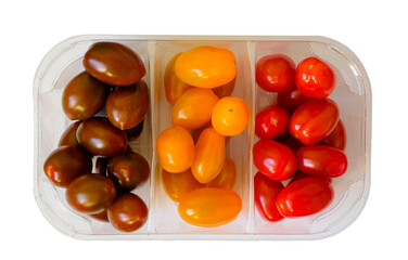 Ripe multicolored tomatoes in clear plastic container isolated. Tricolor of Cherry tomatoes. Plum tomatoes from supermarket. Top view. 