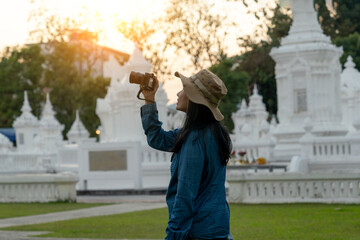 Obraz premium A female tourist capturing the evening atmosphere of a temple in Chiang Mai, Thailand