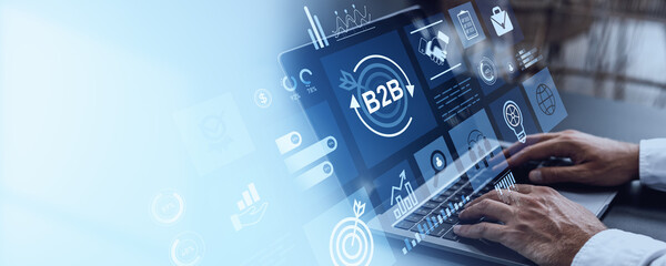 Businessman using laptop with B2B digital interface icons on transparent screen.