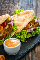 Greek style pita lamb burger with fresh vegetables on wooden table