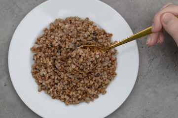 Porcja kaszy gryczanej palonej ugotowanej na sypko na białym talerzyku,