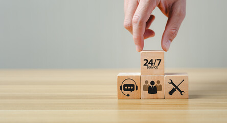 Hand placing a wooden block with "24/7 Service" text on top of other blocks featuring icons of customer support, teamwork, and technical service, representing continuous business support.
