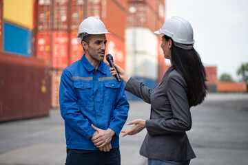 Mature worker in uniform giving an interview to microphone for reporter while they standing in...