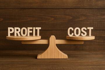 A wooden balance scale displays the words 'Profit' and 'Cost', symbolizing the critical evaluation of financial gains versus expenses in business decisions.
