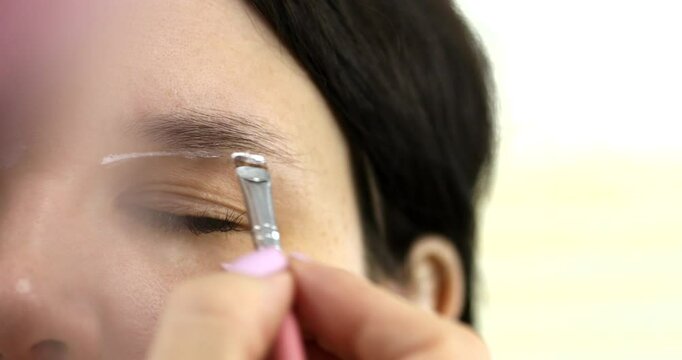 Brow master draws white markup on the eyebrows of a model