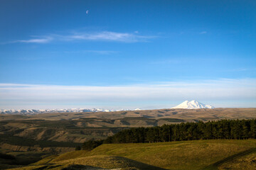 Panoramic landscape with Mount Elbrus under blue sky.
