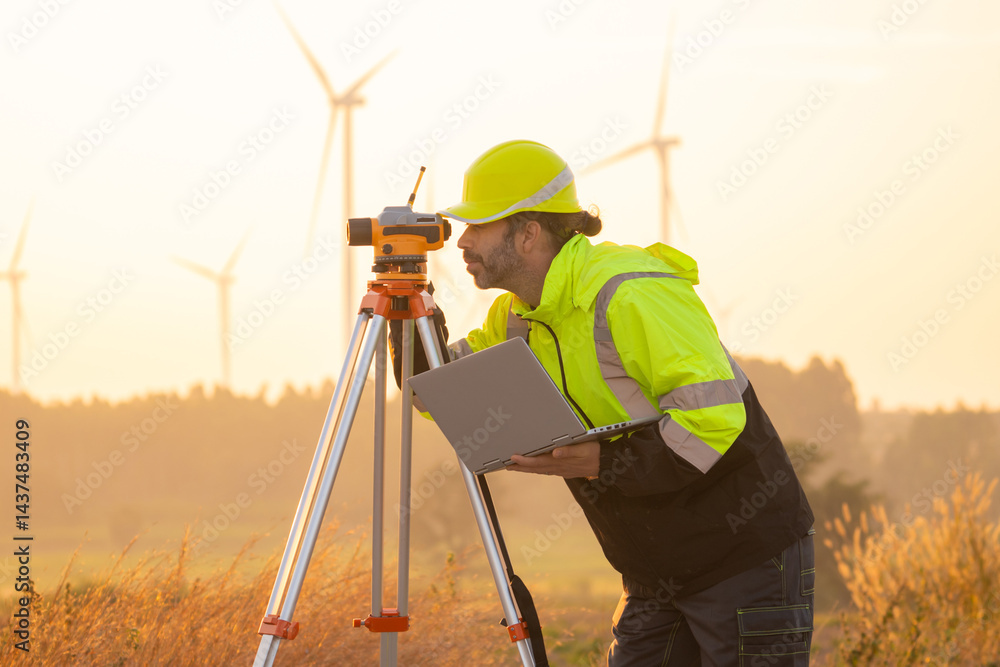 Fototapete Engineer working on laptop in front of wind turbines for checking wind turbines of the field during beautiful sunset. Alternative energy concept.