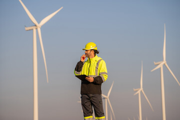 Engineer man working with tablet at windmill farm Generating electricity clean energy. Wind turbine farm generator by alternative green energy.