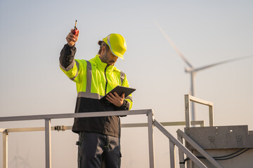 Engineer man working with tablet at windmill farm Generating electricity clean energy. Wind turbine farm generator by alternative green energy.