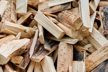 A close-up view of a stack of chopped firewood with natural textures and wood grain, showing split...