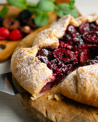 Galette tart with red berries, cherries, raspberries and blackberries. Top view table with christmas decoration.