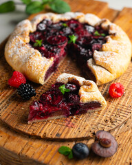Galette tart with red berries, cherries, raspberries and blackberries. Top view table with christmas decoration.