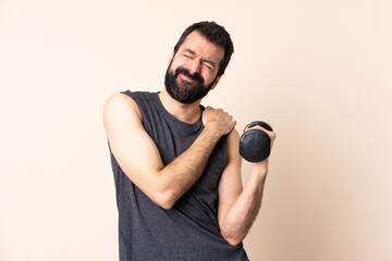 Caucasian sport man with beard making weightlifting over isolated background suffering from pain in...