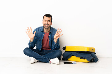Caucasian handsome man with a suitcase full of clothes sitting on the floor at indoors counting...