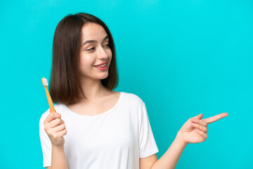 Obraz premium Young Ukrainian woman brushing teeth isolated on blue background pointing to the side to present a product