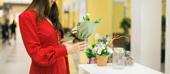 Woman choosing flowers while shopping in mall. Leisure, beauty and lifestyle theme. Banner with copy space