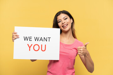 Young Russian girl isolated on yellow background holding We Want You board with thumb up