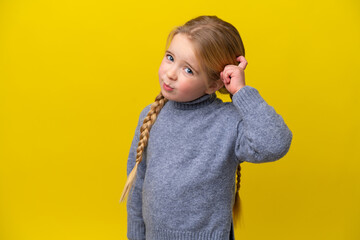 Little caucasian girl isolated on yellow background having doubts and with confuse face expression