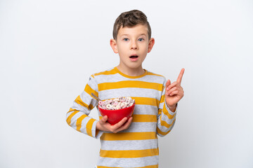 Little caucasian boy holding a cereal bowl isolated on white background thinking an idea pointing the finger up