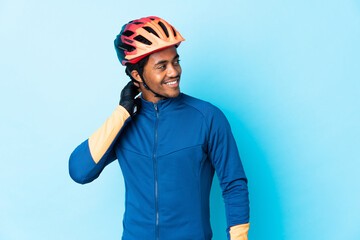 Young cyclist man with braids over isolated background thinking an idea