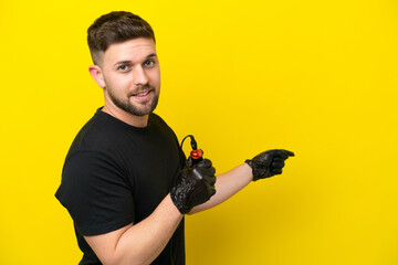 Tattoo artist man isolated on yellow background pointing back
