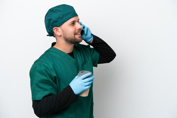 Surgeon in green uniform isolated on white background holding coffee to take away and a mobile